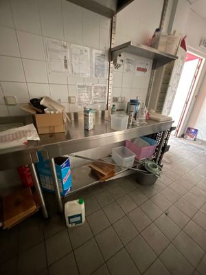 une cuisine équipée d'un grand plan de travail en inox et d'étagères