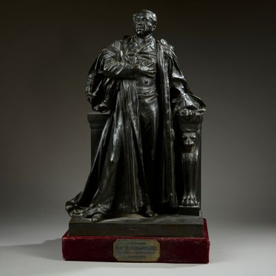 a bronze statue of a man sitting on top of a chair