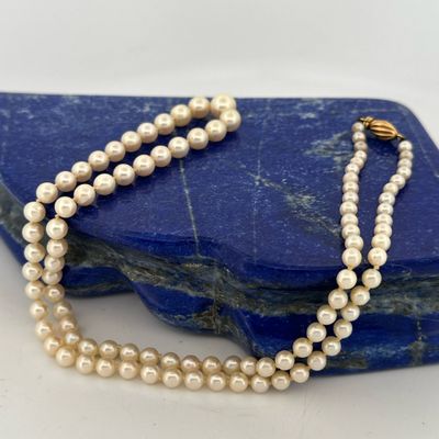 a close up of a white pearl necklace on a blue rock