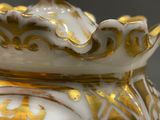 a gold and white vase with a crown on top