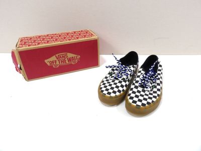 une paire de Slip-On Vans à carreaux à côté d'une boîte rouge