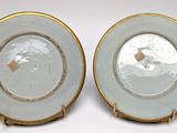 two plates with gold rims are sitting on a white surface