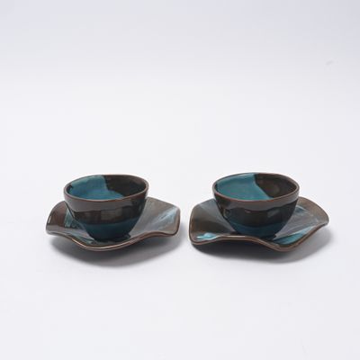 une paire de tasses à thé et de soucoupes posées sur une surface blanche