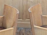 two wooden chairs sitting next to each other on a wooden floor