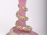 a pink glass with a snake on top of it