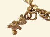 a gold chain with a teddy bear charm hanging from it