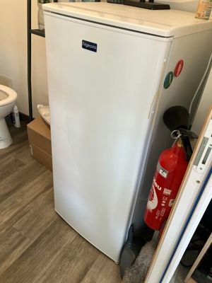 un réfrigérateur blanc et des toilettes dans une petite pièce