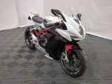 une moto blanche et rouge garée sur un sol à carreaux noirs