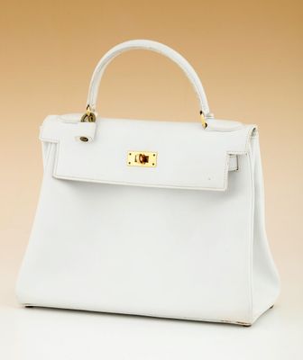 a white handbag with gold hardware on the handle