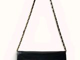 un sac à main noir auquel est suspendue une chaîne dorée