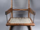 an old wooden rocking chair with a roped seat on a gray background