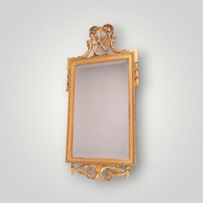 a gold framed mirror with a decorative design on the wall
