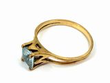 a close up of a gold ring with a blue topaz stone