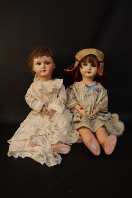two dolls sitting next to each other on a black surface