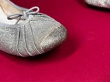 pair of silver shoes on a red surface with a red background