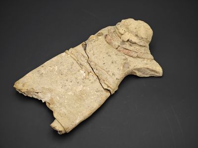 une ancienne figurine en pierre représentant un homme coiffé d'un chapeau