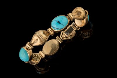 un gros plan d'un bracelet en or orné de pierres de turquoise