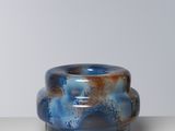 un vase bleu et marron posé sur une table blanche