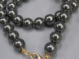 un gros plan sur un collier de perles noires muni d'un fermoir doré