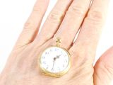 a person holding a small gold pocket watch in their hand