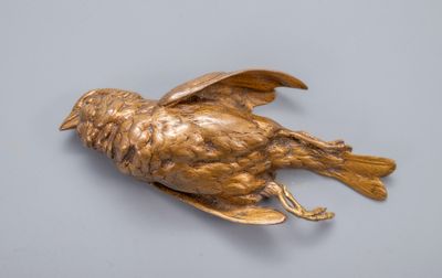 oiseau en bronze sur une surface grise