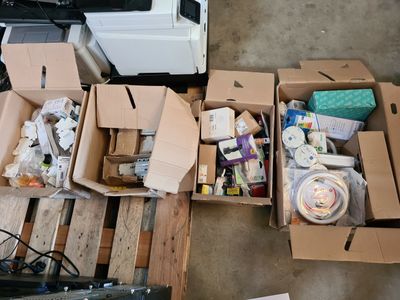 Plusieurs cartons contenant des articles divers sont posés sur une palette dans un garage.