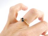a person ' s hand holding a gold ring with a black diamond