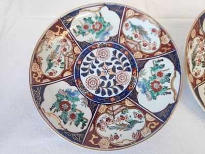 two plates with different designs on them sitting on a white surface