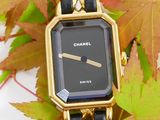 a gold watch with a black face on a chain bracelet