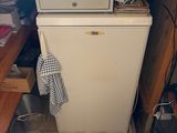 a small white refrigerator in the corner of a kitchen