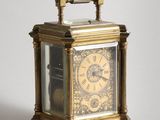 a small brass clock with a glass case on it