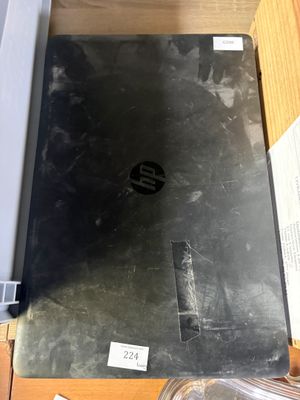 un ordinateur portable posé sur un bureau, à côté d'un récipient en plastique