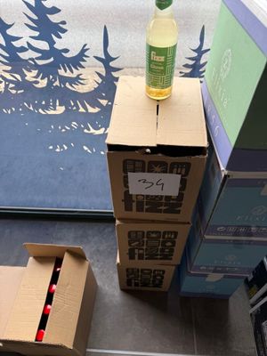 a bottle of wine sitting on top of a cardboard box next to a cardboard box