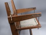 an old wooden rocking chair with a rope on the back of it