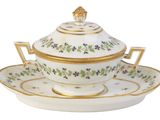 un plateau blanc et doré sur lequel sont posés une tasse et une soucoupe