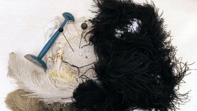 un ours en peluche noir et blanc assis au sommet d'un tas de plumes