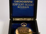 a gold pocket watch in a black box on a white surface