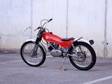 a red motorcycle parked in a parking lot next to a white wall