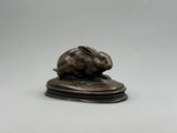 une figurine antique en bronze représentant un lapin sur un socle