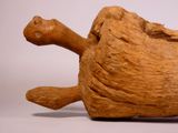 a wooden duck that is laying down on the ground