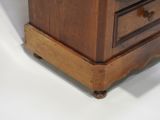 a small wooden chest of drawers on a white surface
