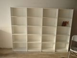 a white bookcase in the corner of a room with a chair