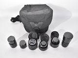 a lot of camera lenses and a bag on the table