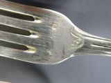 two silver spoons and a fork on a table