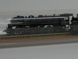 un train miniature dans une vitrine, posé sur un socle en bois