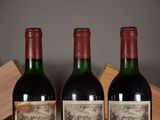 three bottles of red wine sitting on top of a wooden crate