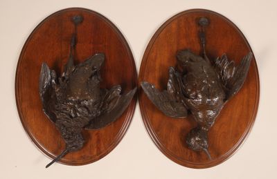 paire de têtes d'oiseaux en bronze fixées sur des plaques en bois accrochées au mur