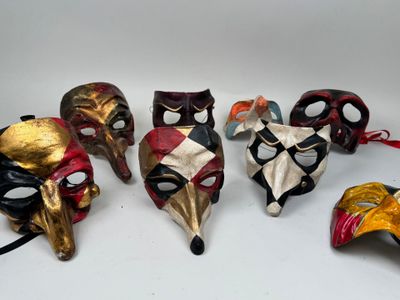Plusieurs masques de différentes couleurs sont alignés sur une surface blanche.