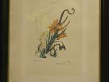 painting of a yellow flower in a black frame on a table