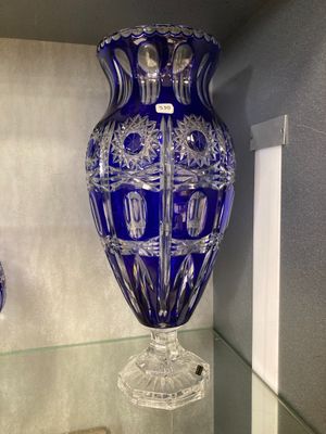un vase bleu posé sur une étagère en verre dans une pièce